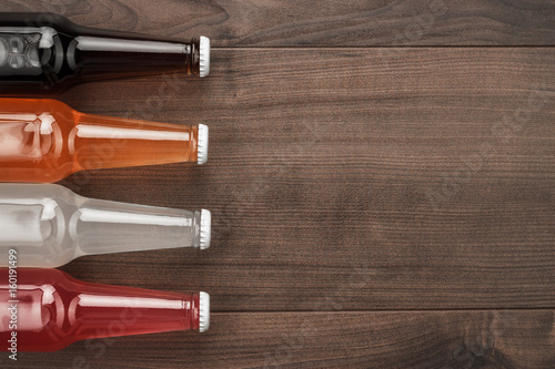 glass bottles of different sweet drinks on wooden table