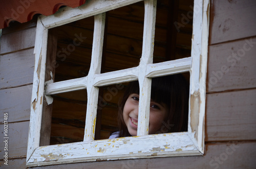 Niña hispana observando a través de la ventana