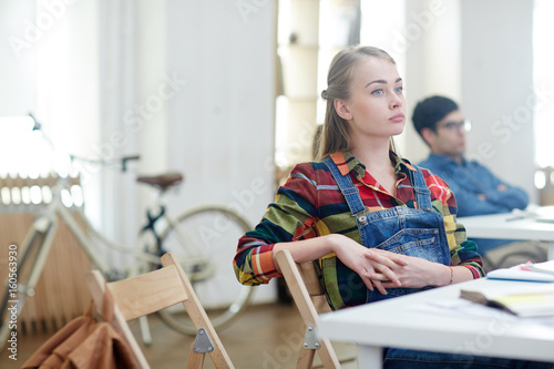 Absent minded girl sitting by desk at lesson