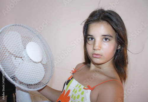 the girl is saved from the heat by the fan,very hot.