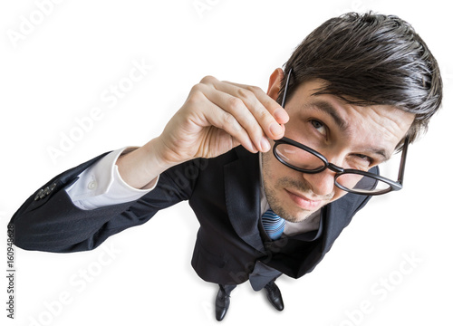 Young skeptic man with glasses is looking at you. View from above. Isolated on white background.