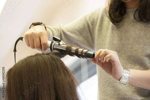 Hairdresser is wearing female hair with iron