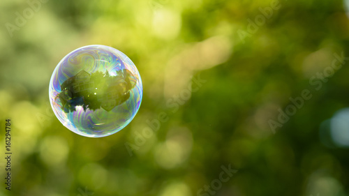 House reflection in soap bubble on green, blurred background. Dream home. 