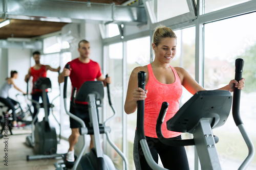 People doing on elliptical trainer in gym