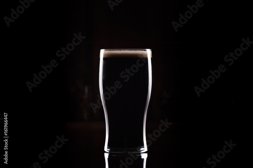 Stout (Guinness like) Beer in pint glass, silhouette with perfect head and dark background