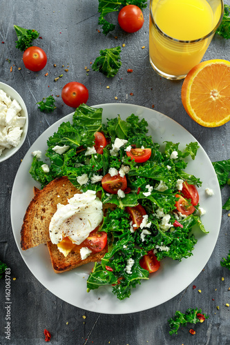 Breakfast Green Kale with poached eggs, feta cheese, tomatoes and toast. healthy food