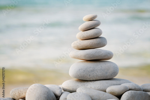 Stack of white pebbles stone against sea background for spa, balance, meditation and zen theme.