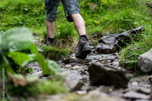 Junger Mann beim wandern durch einen Bach