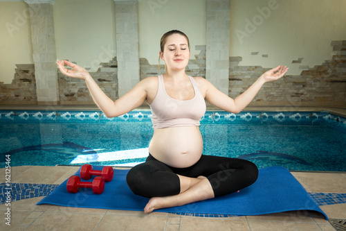Pregnant woman doing yoga at fitness club