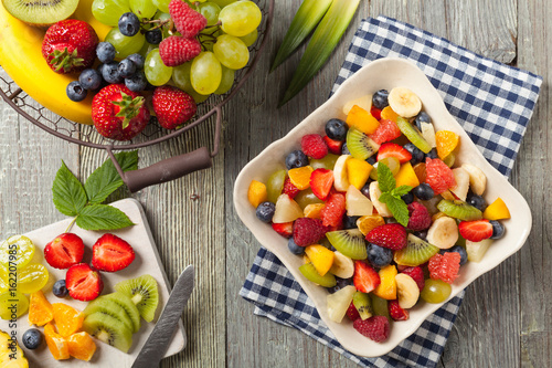 Delicious fruit salad with fresh fruit. Wooden, gray table in the background.