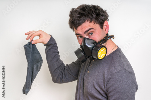 Man with gas mask is holding dirty stinky sock
