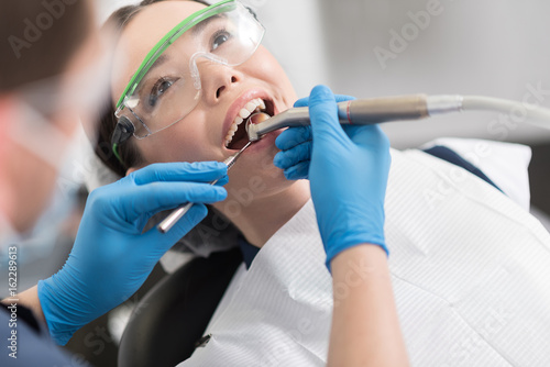 Doctor curing teeth of outgoing girl