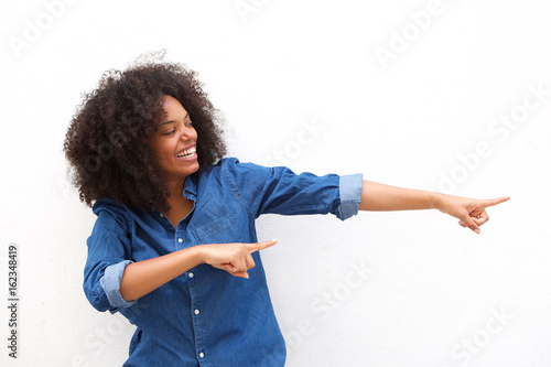 Smiling beautiful woman pointing to the side against white background