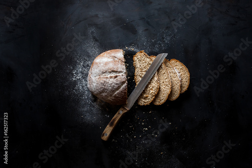 Sliced ​​bread and a knife lying on a black metal table