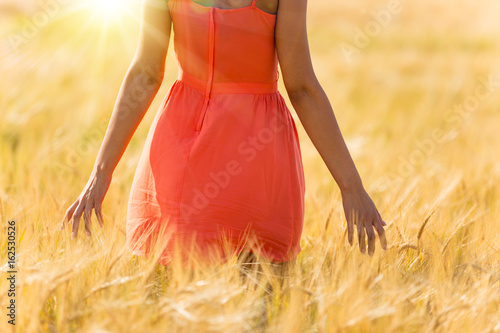 Girl in red dress walking on wheat field