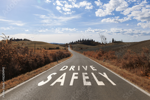 Concept drive safely message on the sunny summer asphalt country road. Conceptual safe driving alert background.