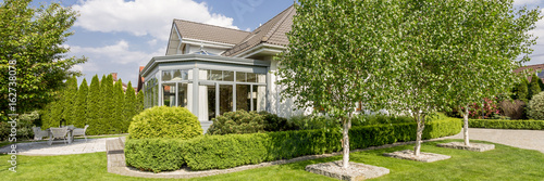 House exterior with orangery in well-kept garden