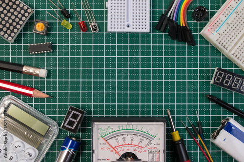 DIY electrical maker tools components on green cutting mat board. DIY electrical maker tools with copy space for text on green background. DIY electrical handmade tools electronic maker components.