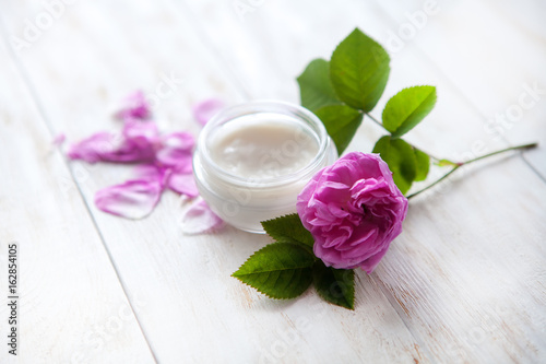 organic cosmetic with rose and pot of moisturizing face cream on white background