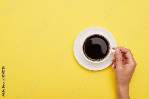Flat lay of cup of delicious coffee in woman hand