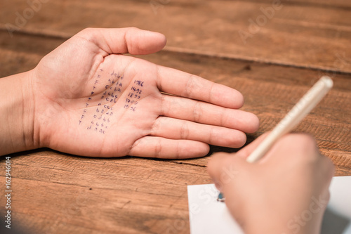 People cheating on test by writing answer on hand