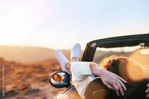 Young woman enjoying the sunset from a convertible