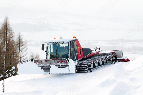 Red winter ratrak parked in slope in the snow.