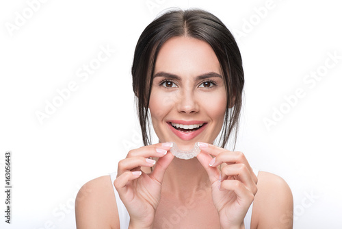 Excited young woman holding clear aligner