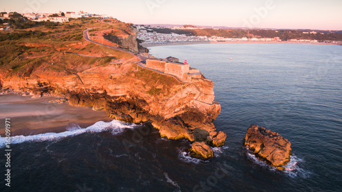 Aerial view of ocean and Nazare lighthouse at sunset, Portugal