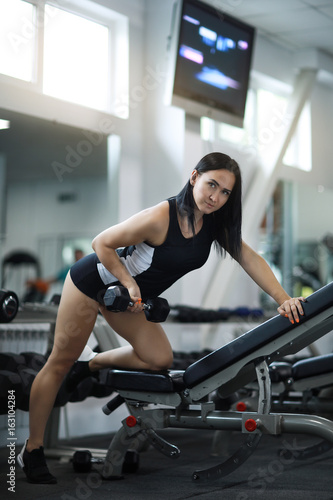 Young beautiful girl is at the gym in tight-fitting tracksuit 