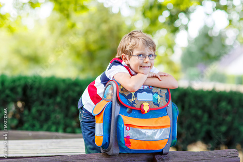 little kid boy with school satchel on first day to school