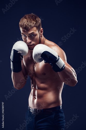 Aggressive shirtless boxer on dark smoke background.