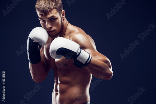 Aggressive shirtless boxer on dark smoke background.