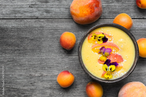 bowl of homemade yellow smoothie with fresh mango, peaches and apricots