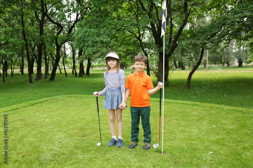 Cute children on golf course in summer day