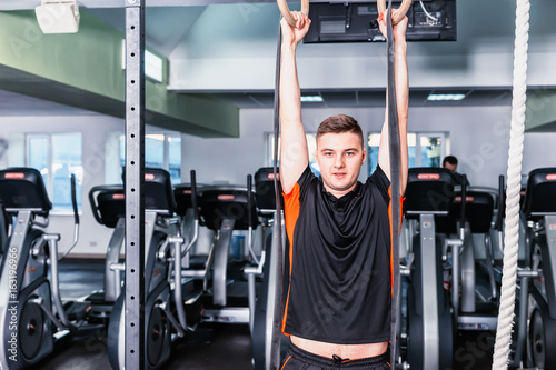 Sportive young man in sportswear working out in a gym
