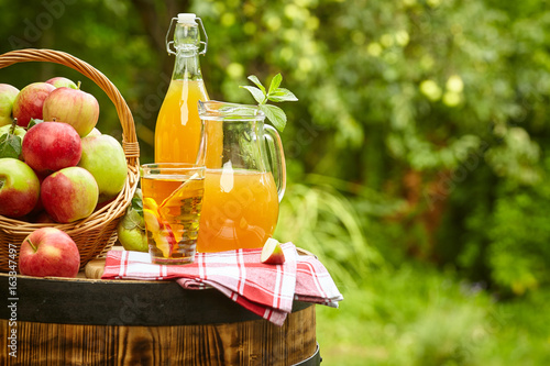 Basket of apples on background orchard standing on a barrel. Apple juice and apple preserves.