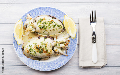 Top view of cuttlefish with hajo, parsley and lemon next to fork and napkin. Food.