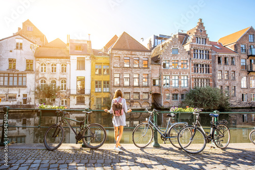 Sunrise view on the water channel with beautiful old buildings with woman standing near the bicycles in Gent city