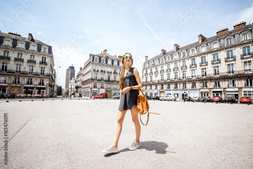Young woman walking with bag on saint Pierre square with famous Brittany tower on the background in Nantes city in France