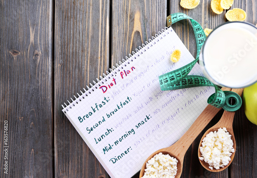 Diary and different dairy products on wooden background