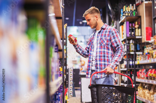 Young man shopping in a supermarket holding shopping cart