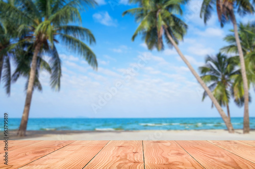 Wooden table in front of abstract blurred sea & coconut tree background. For present your products. Summer Concept