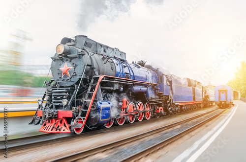 Vintage black steam locomotive train rush railway station. Concept of tourism is a retro journey by train