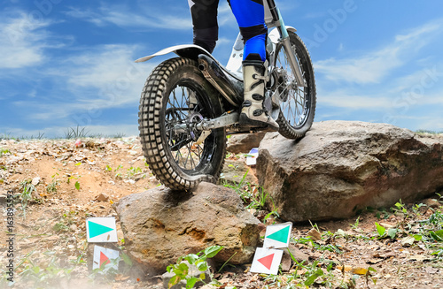 Trials motorcycle is jumping over rocks
