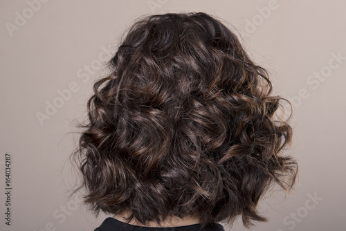 Hairstyle short Ringlets of dark hair on isolated grey background