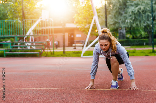 Athletic woman on running track getting ready to start run.