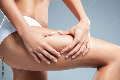 Young woman on grey background. Cellulite problem concept