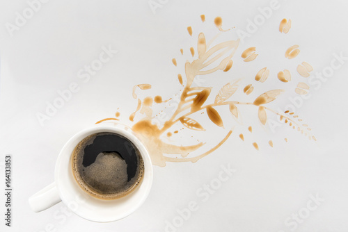 top view of cup of coffee and brown stains in floral shape on grey