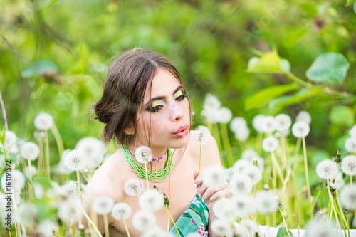 woman with fashionable makeup and beads in green leaves